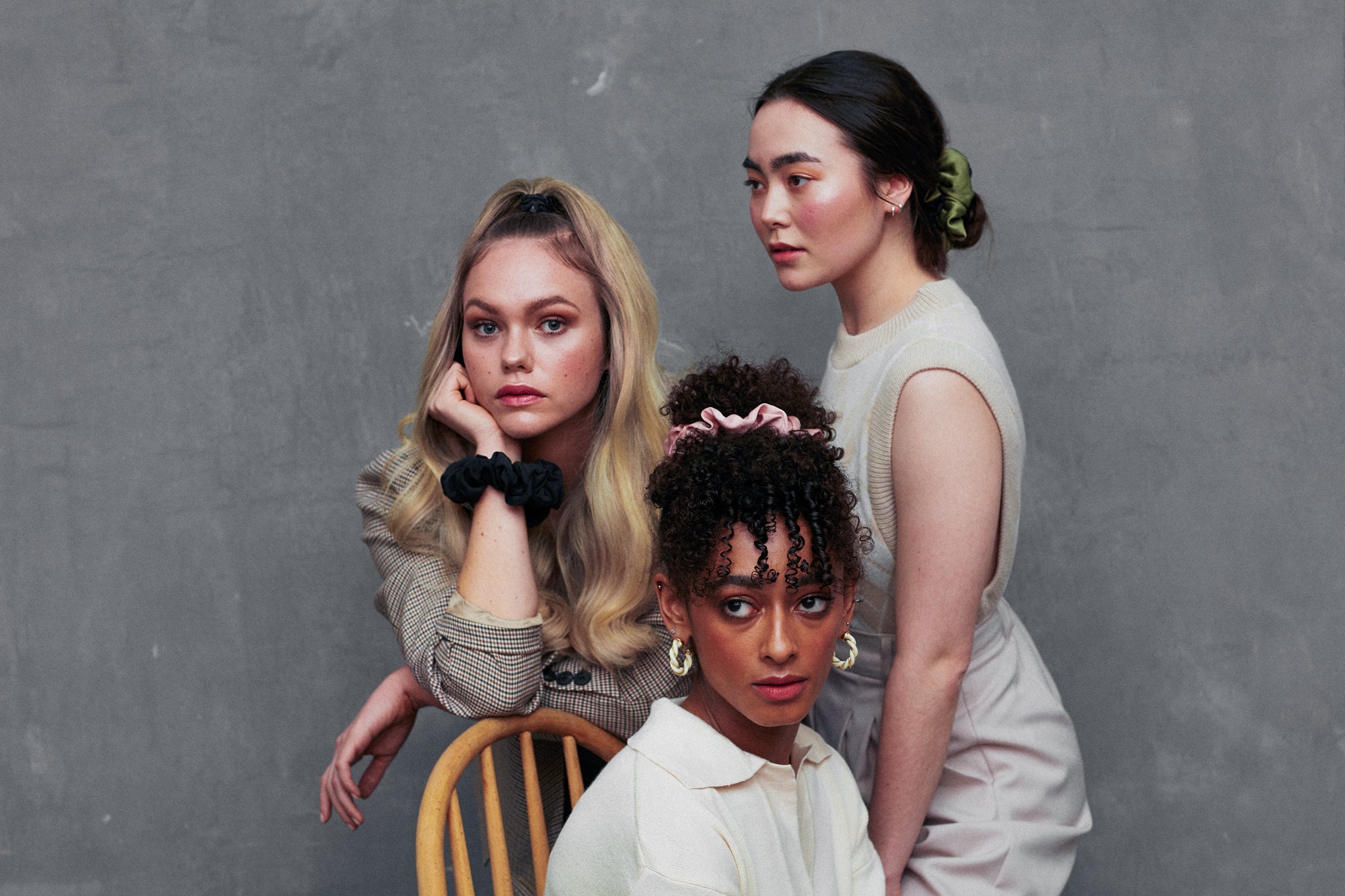 3 women all wearing silk scrunchies in their hair, in pink, green and black silk
