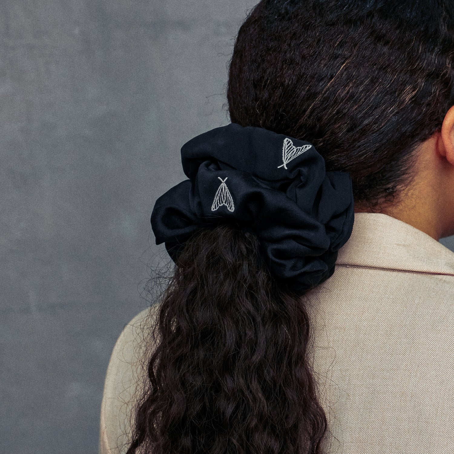 Two large black silk scrunchies in a ponytail made from ethical peace silk with moth embroidery