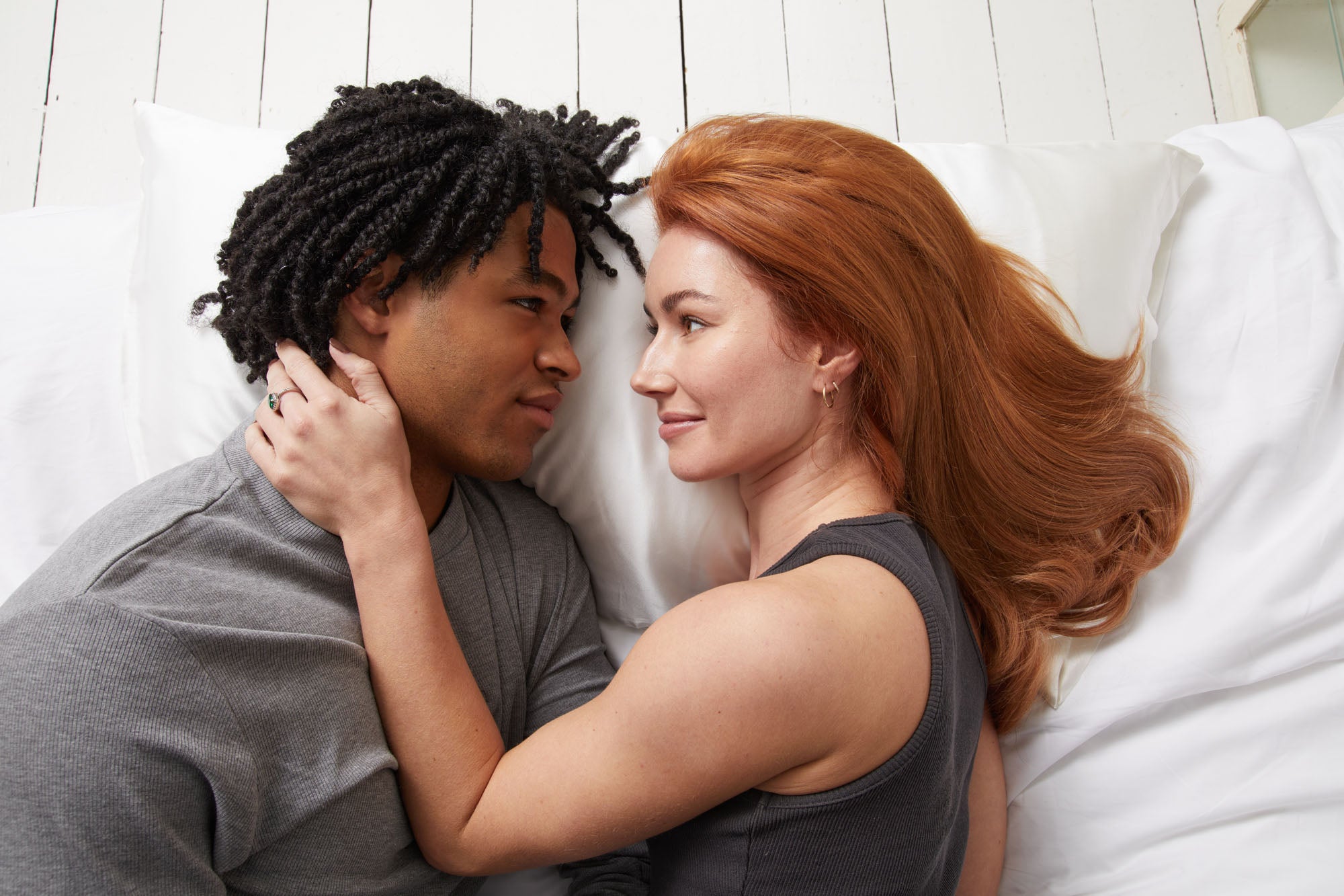 Couple lying on white silk pillowcases