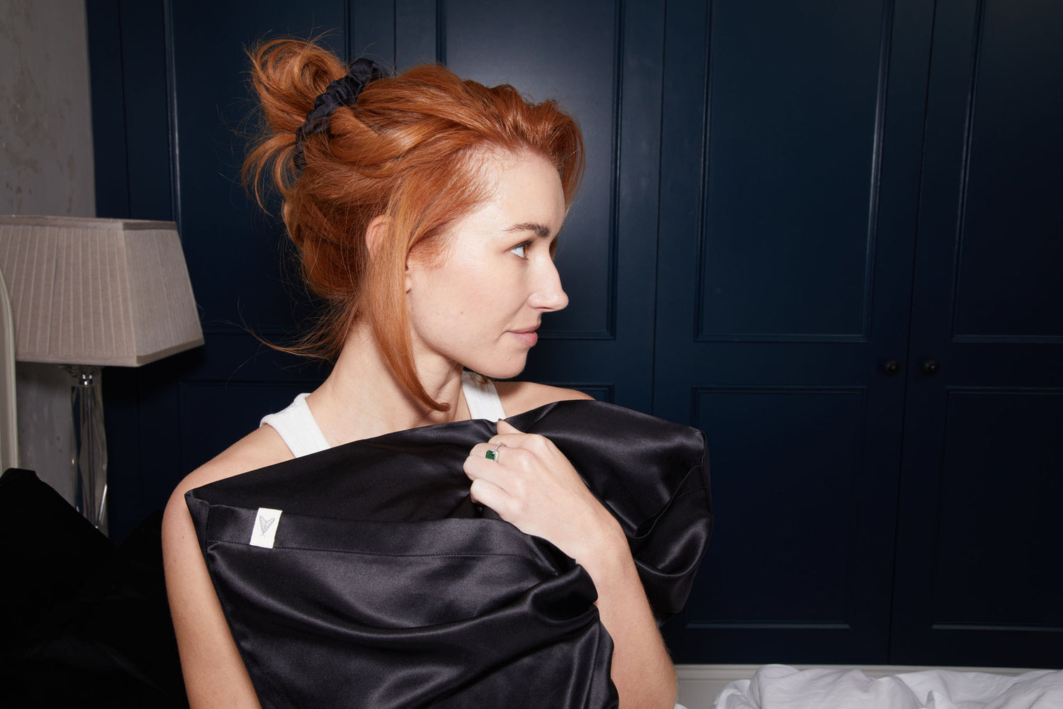 Woman holding black peace silk pillowcase and wearing black peace silk scrunchie in her hair