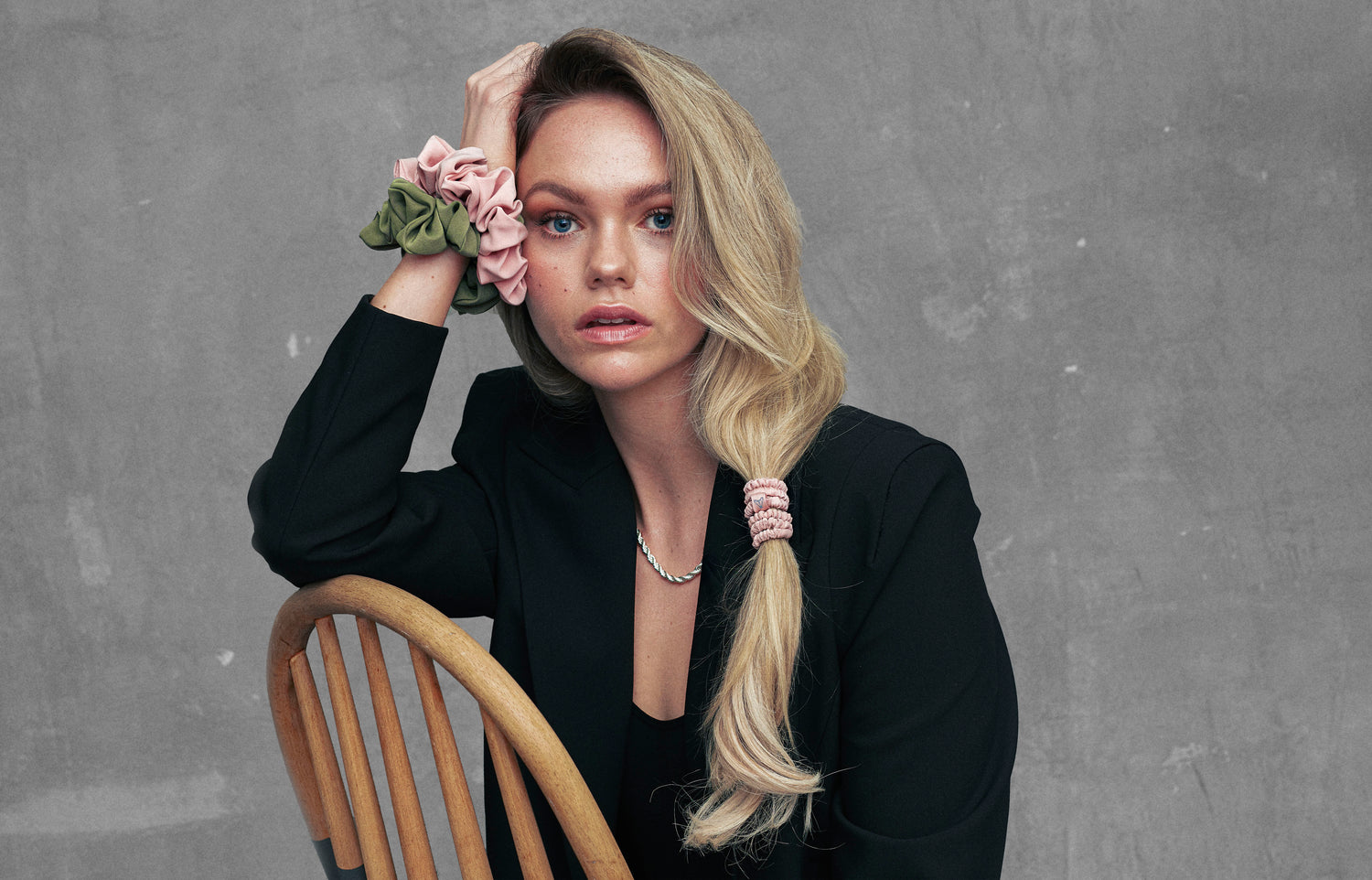 Woman wearing large silk scrunchies on her wrist in green and pink silk and narrow pink silk hair ties in her hair